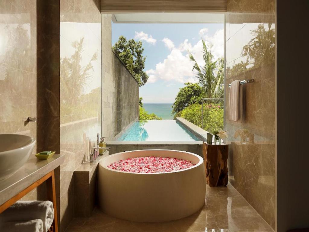 round bath with flowers overlooking a swimming pool and sea view