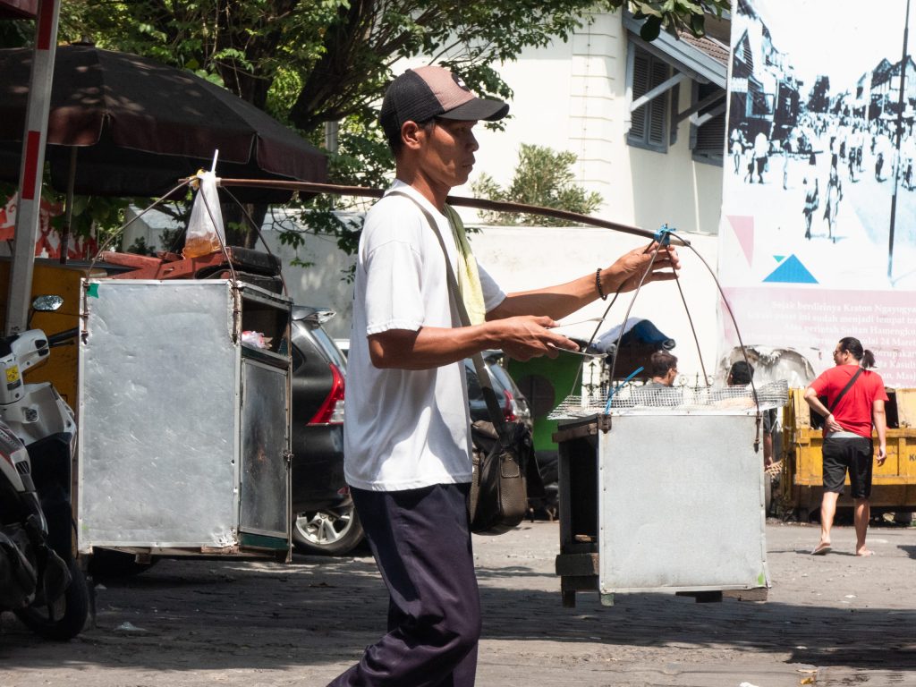 street food vendor in indonesia carrying metal boxes