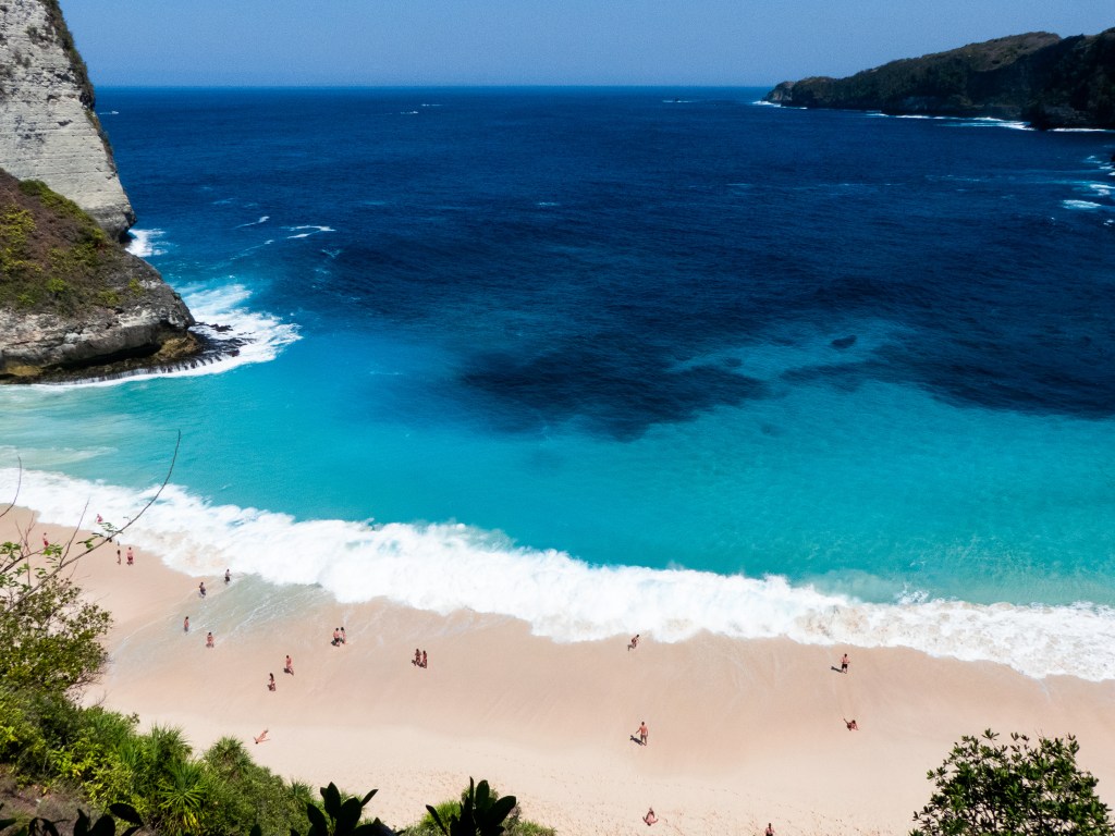 Beach Indonesia blue water cliff, white sand people