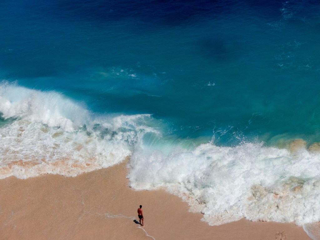 beach with person white sand blue water big wave