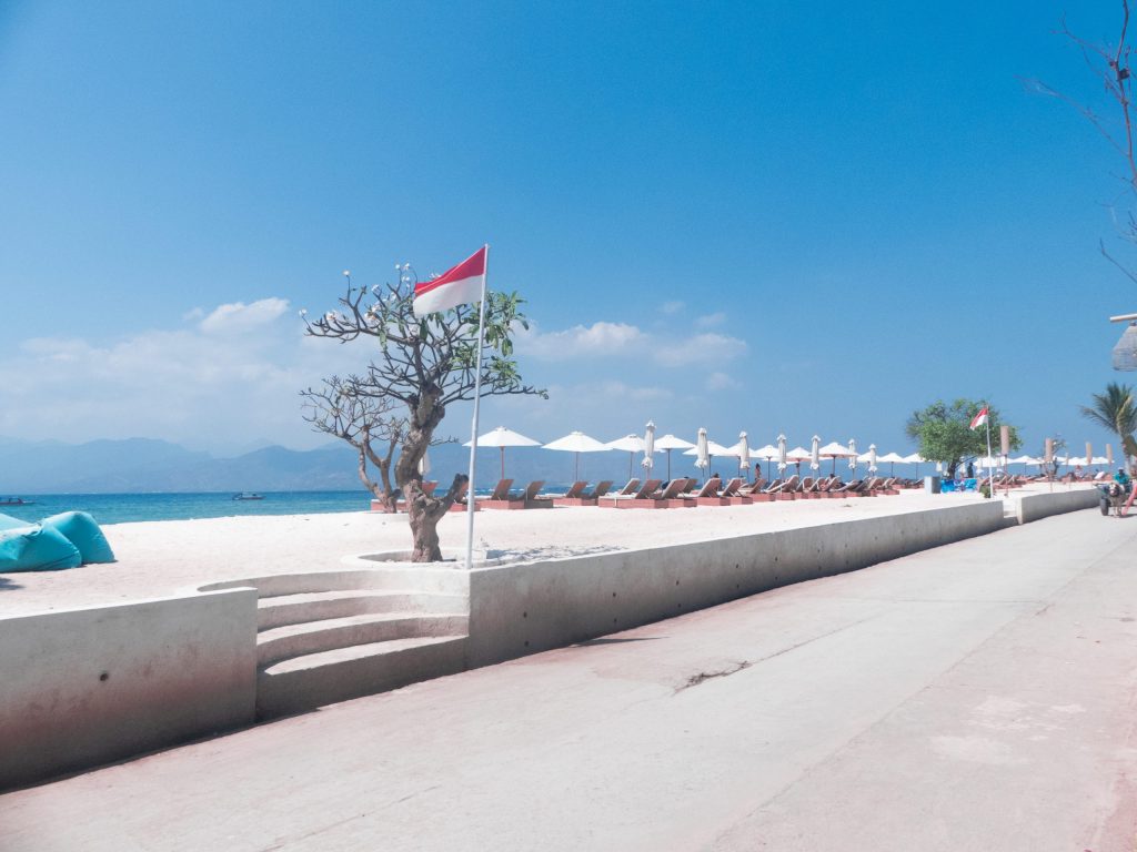 beach road in gili trawangan with ocean view, indonesian flag and sun umbrellas