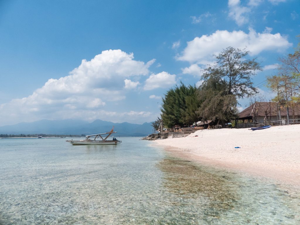 beach with shallow waters and boat blue sky 