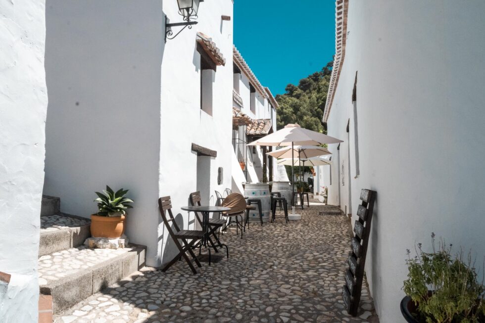 white village in spain with narrow alleyway and cobblestone road