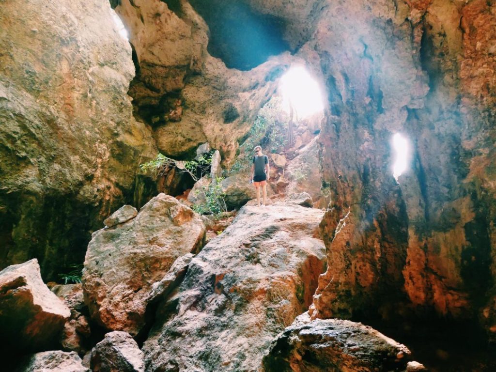 cave with light shining through man standing