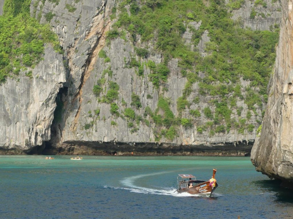 boat turning a corner at a limestone cliff in thailand