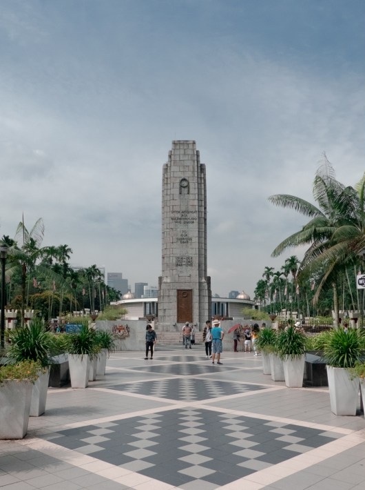 national monument kuala lumpur blue sky and palm trees