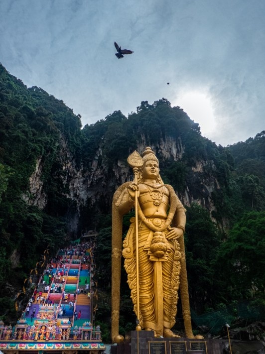 batu caves gold statue blue sky and rainbow steps which is the perfect cheap or free activity in KL