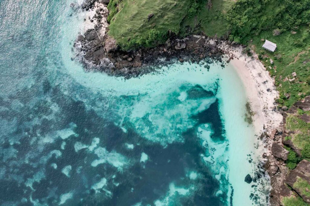 Drone shot Indonesia Kuta Lombok mountain rocks blue water white sandy beach