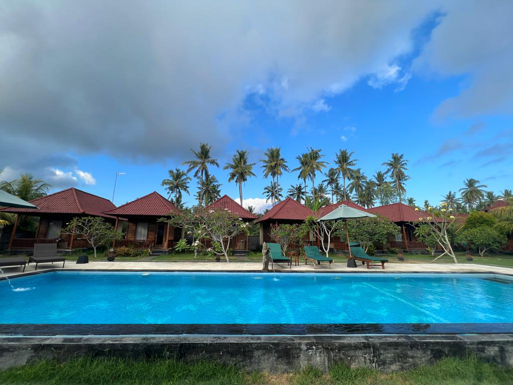 pool cloudy sky palm tree bungalows