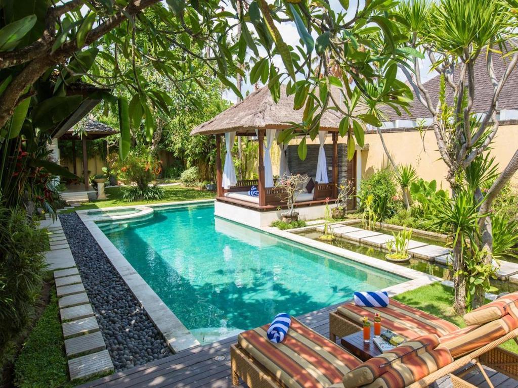 Villa with private pool, sun loungers surrounded by tropical garden 