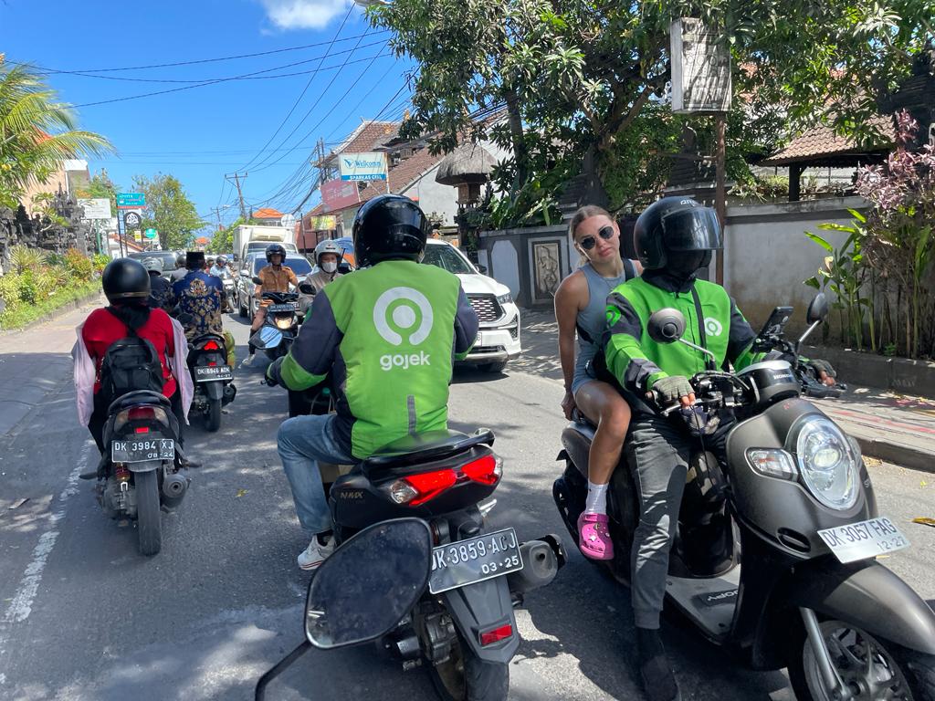 gojek drivers with passenger green jackets on scooters