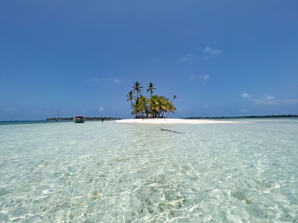 sand island with palm trees in panama surrounded by crystal clear waters and blue sky making for the best one word travel captions