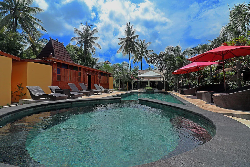 pool with red sun umbrellas and palm trees