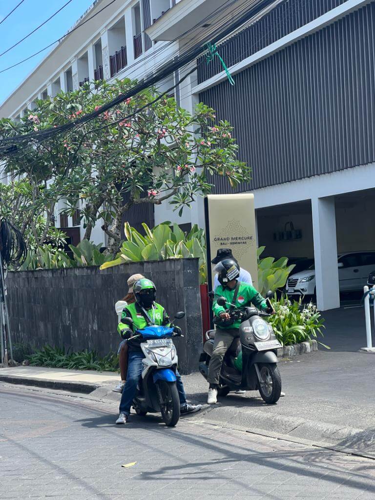 gojek and grab drivers in seminyak with passenger by the side of the road 