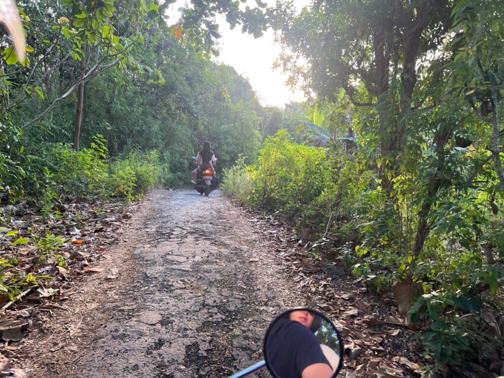 bumpy dirt road in nusa lembongan with scooters and potholes