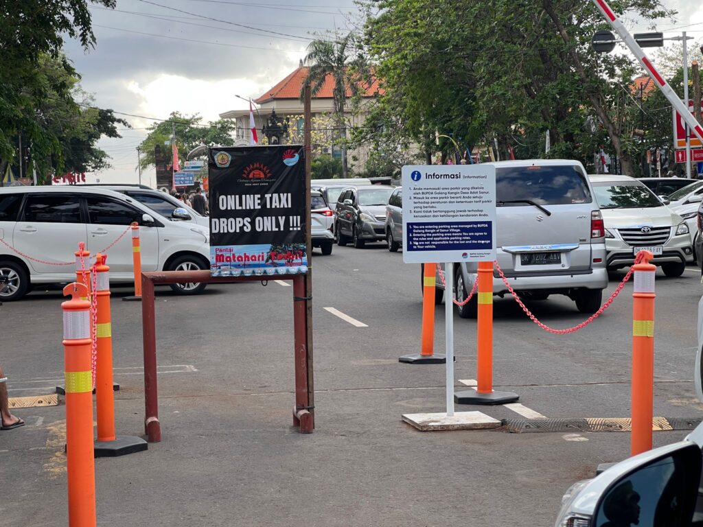 no gojek zone sign in sanur at the harbour in bali with orange signposts and cars