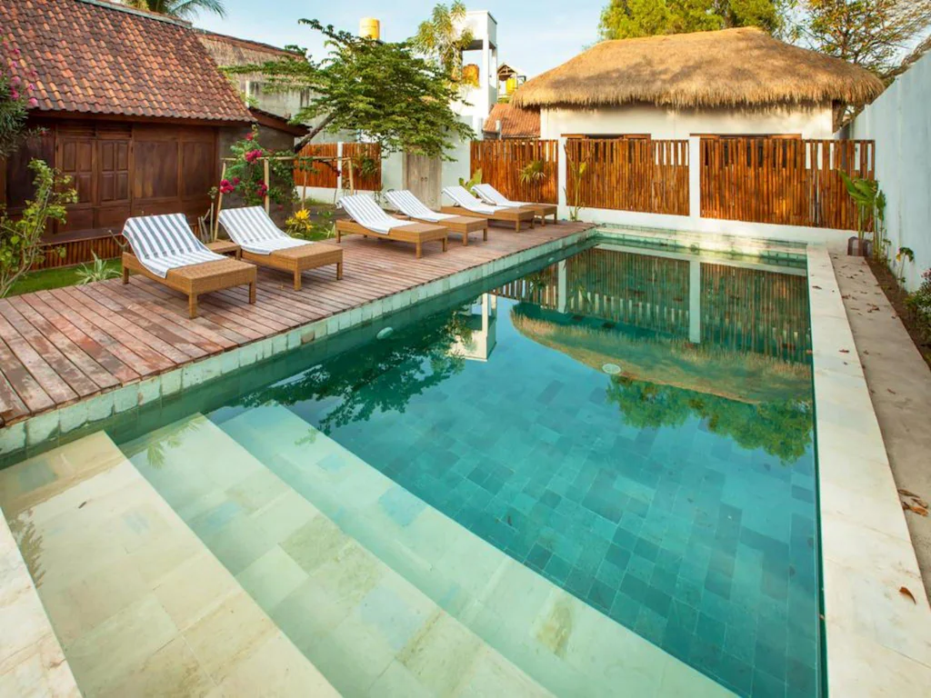 hotel with pool and sun loungers huts in the background