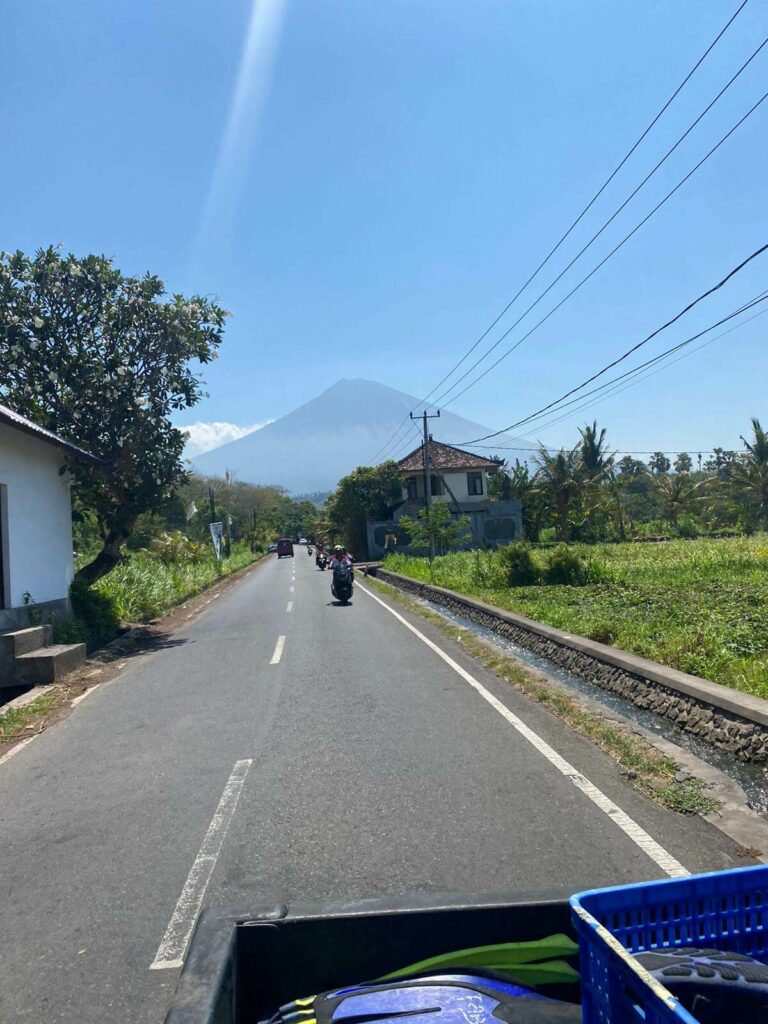 road in amed with view of volcano and rice fields under blue sky