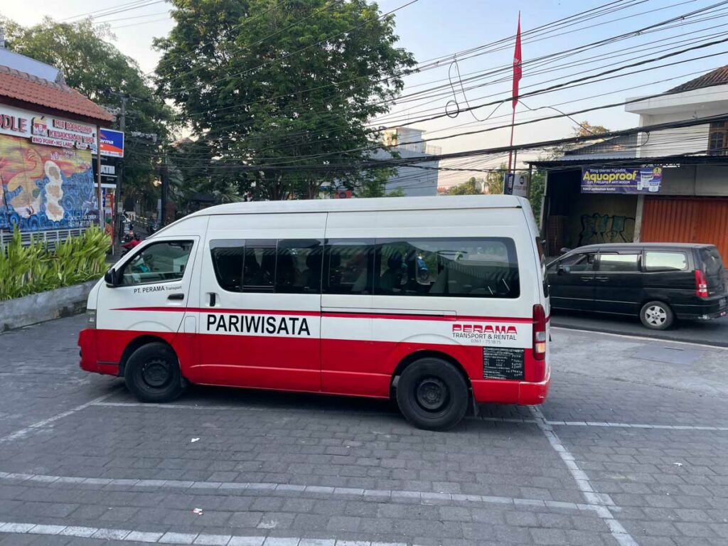 Perama bus shuttle Bali red and white minivan in parking lot public transport