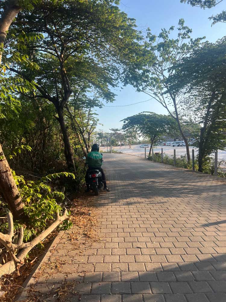 Uluwatu Temple parking lot grab pickup point gojek driver waiting on bike under trees