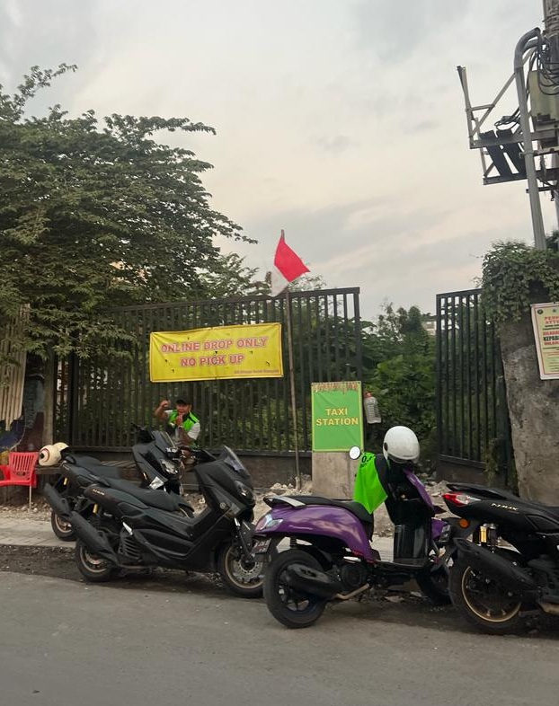 no gojek zone echo beach canggu taxi madia driver waving with yellow sign behind scooters