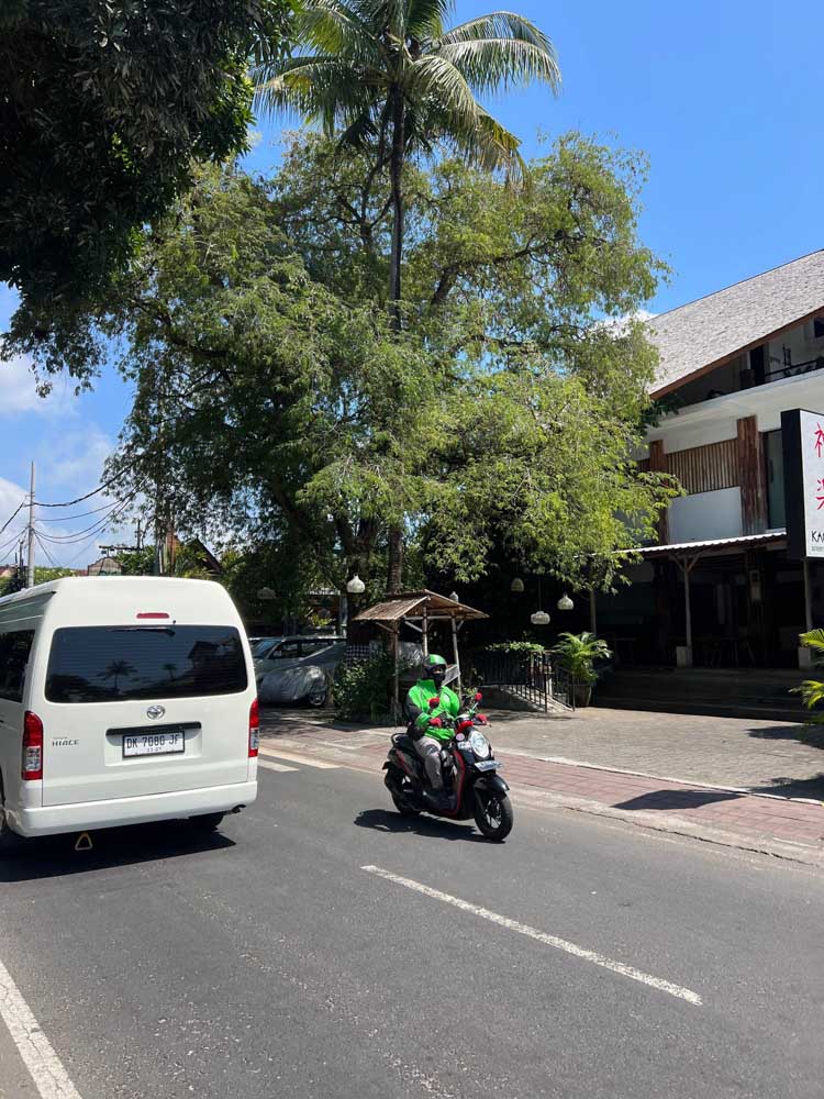 gojek or grab driver with green jacket on bike in nusa dua