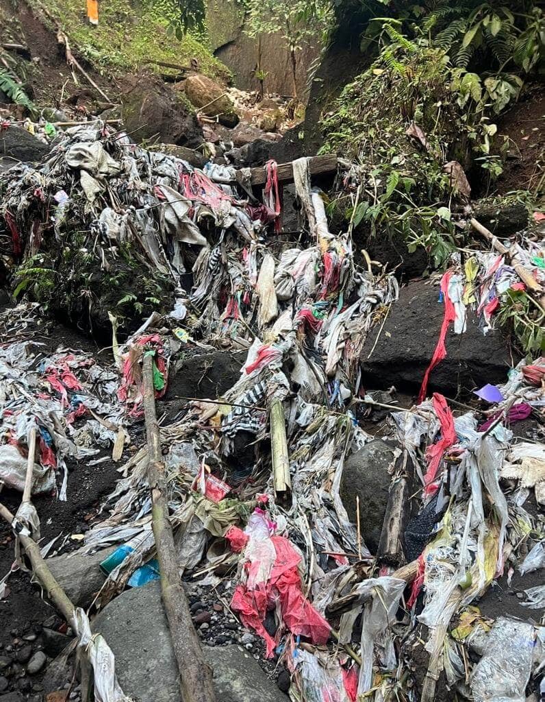 trash plastic waste and pollution at waterfall in bali river sidemen