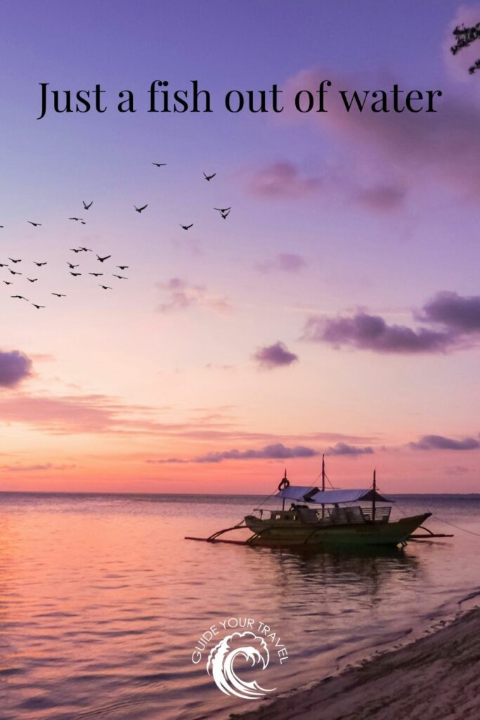 A traditional boat floats on calm waters at sunset. Island quotes and captions for Instagram