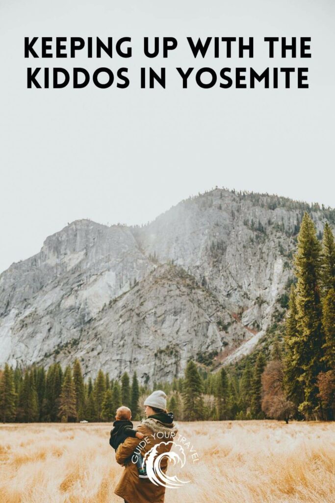 An adult and a child in a meadow with cliffs.