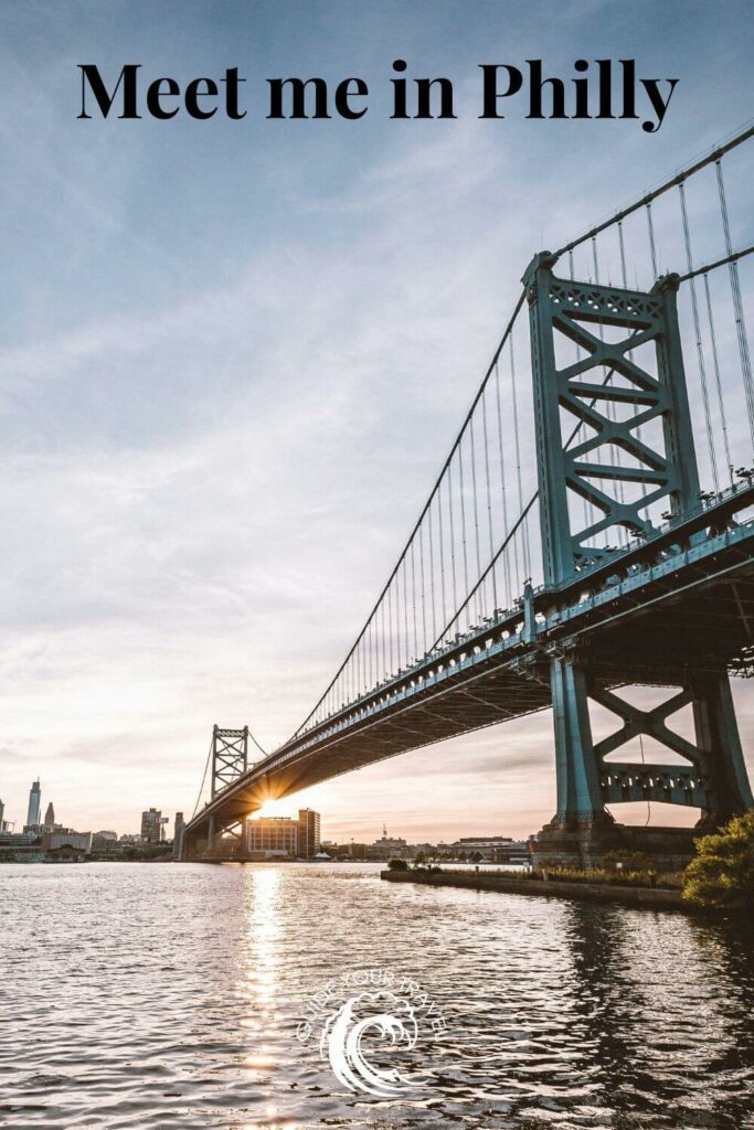 A bridge spans over a river at sunset, with the city skyline in philadelphia perfect for instagram captions and quotes