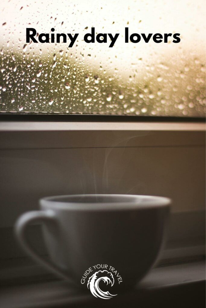 A steaming cup of coffee by a rain-speckled window perfect for rainy day Instagram captions and quotes.