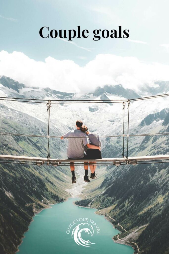 A couple sitting on a high bridge overlooking a valley with the best two-word instagram captions