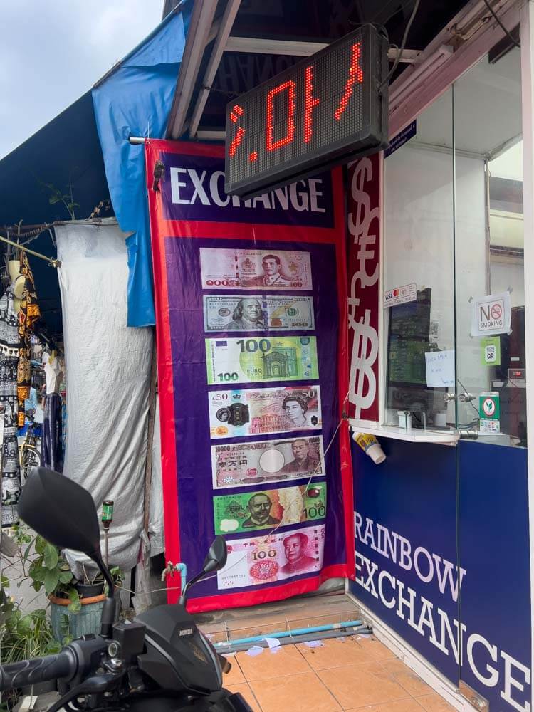 currency exchange office in thailand with banner including different bills such as us dollars, euros and rupees