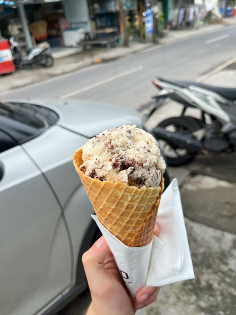 Dop ie cream cone with scoop held in a hand